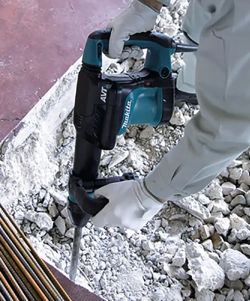 Makita HM0871C udarni čekić u upotrebi na gradilištu, rukom u zaštitnim rukavicama.