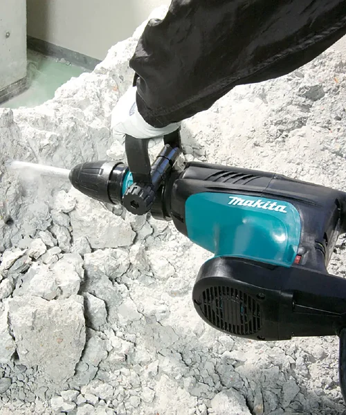 Makita HM1203C udarni čekić u upotrebi na građevinskom gradilištu, prikazuje rad s kamenjem.