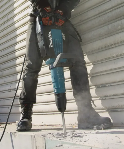 Makita HM1214C udarni čekić u upotrebi na betonskom podu, prikaz radnog procesa.