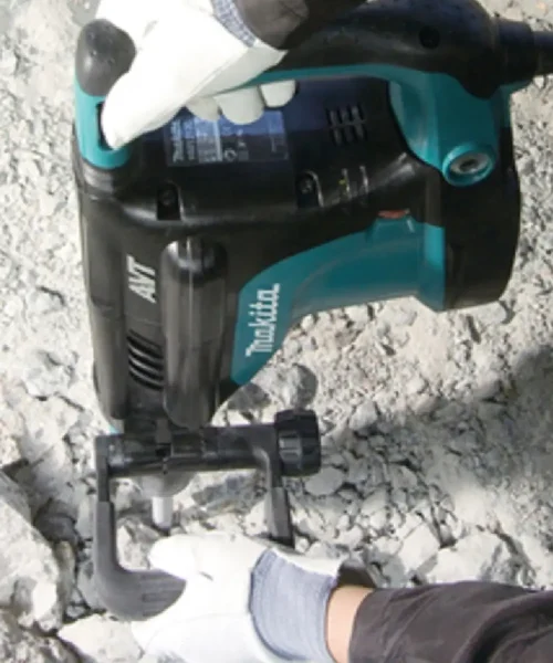 Makita HM1213C udarni čekić u ruci s rukavicama na gradilištu.