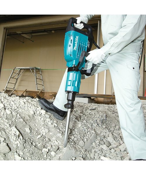 Makita HM1317C udarni čekić u upotrebi na građevinskom gradilištu, prikazan s radnikom u zaštitnoj odjeći.