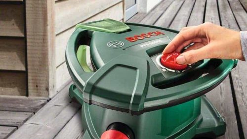 Bosch PFS 5000 E sustav za prskanje boje s crvenim prekidačem i zelenim kućištem na drvenoj terasi.