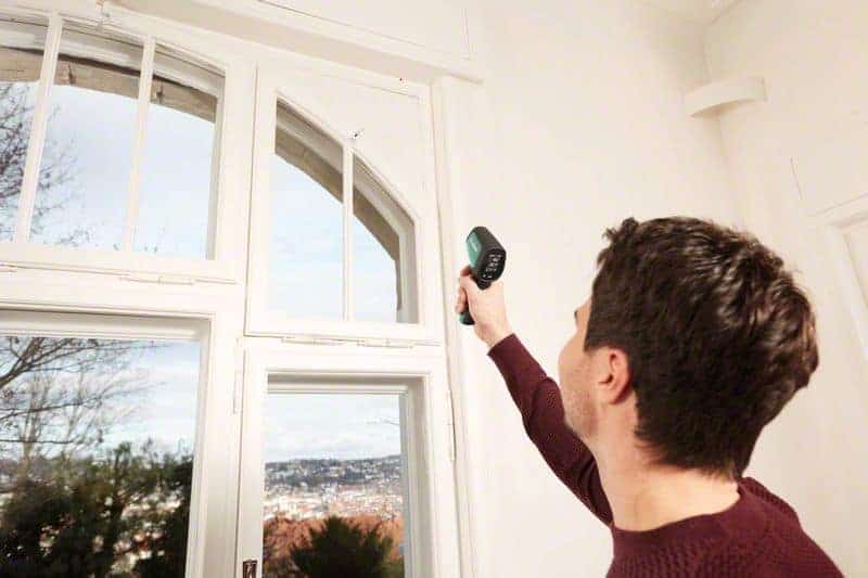 Muškarac drži Bosch UniversalTemp termodetektor usmjeren prema prozoru za mjerenje temperature.