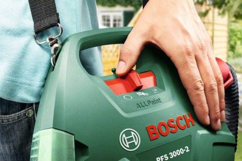 Ruka drži Bosch PFS 3000-2 sustav za prskanje boje, zeleno crveni uređaj za bojanje.