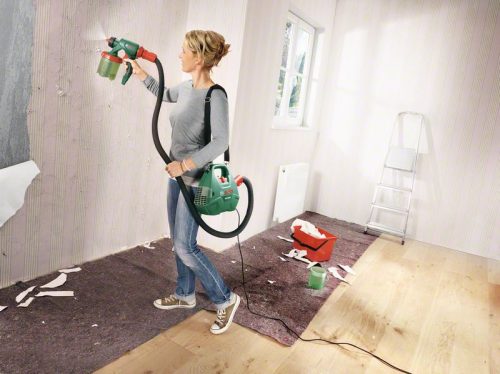 Žena s Bosch PFS 3000-2 uređajem za prskanje boje na bijelom zidu u sobi.
