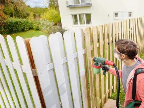 Muškarac s Bosch PFS 3000-2 sustavom za prskanje boje bojom na drvenom ogradi.