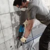 BOSCH bušaći čekić GBH 240 Čovjek koristi Bosch GBH 240 bušaći čekić za bušenje zida s keramičnim pločicama.