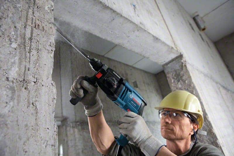 Radnik s Bosch GBH 2-20 D bušaćim čekićem buši beton na gradilištu.