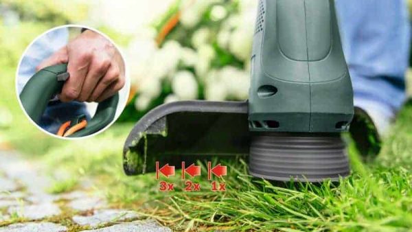 Ruka drži BOSCH EasyGrassCut 23 električni trimer za travu, prikazan na travnjaku s oštrim rezom trave.