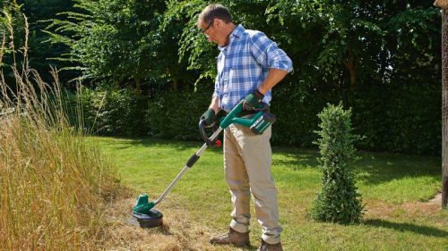 Muškarac koristi Bosch AdvancedGrassCut 36 aku trimer za travu na vrtu.