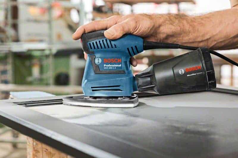 Ruka drži Bosch PRO GSS 160 Multi oscilirajuću brusilicu tijekom obrade površine.