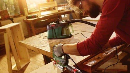 Čovjek koristi Bosch EasyVac 3 usisavač za čišćenje drvenog komada u radionici.