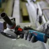 BOSCH kutna brusilica PRO GWS 14-125 S Ruka drži Bosch GWS 14-125 S kutnu brusilicu s crvenim prekidačem i zaštitom na disk.