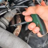 Ruka drži Bosch T-ručka za odvijače dok radi na motoru vozila.
