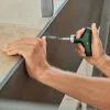 Ruka koristi Bosch odvijač s bitovima za pričvršćivanje ploče namještaja.