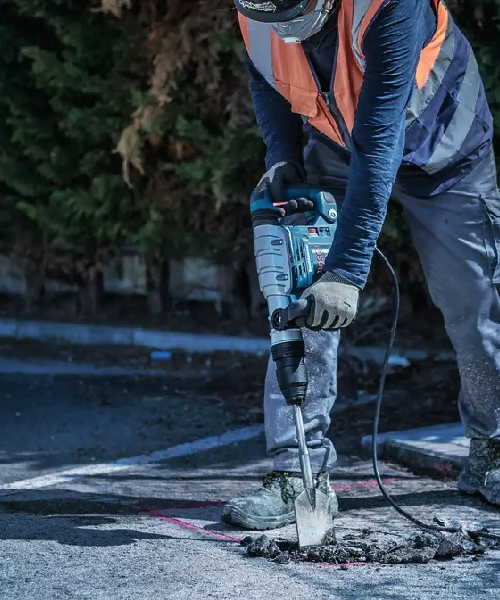 Radnik koristi Bosch SDS-max dlijeto za asfalt na gradilištu, prikazuje alat u akciji.