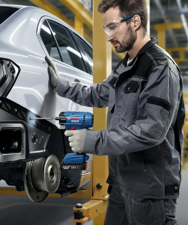 Radnik s Bosch aku odvijačem INDUSTRIAL ISR 18V-50E na automobilu u radionici.