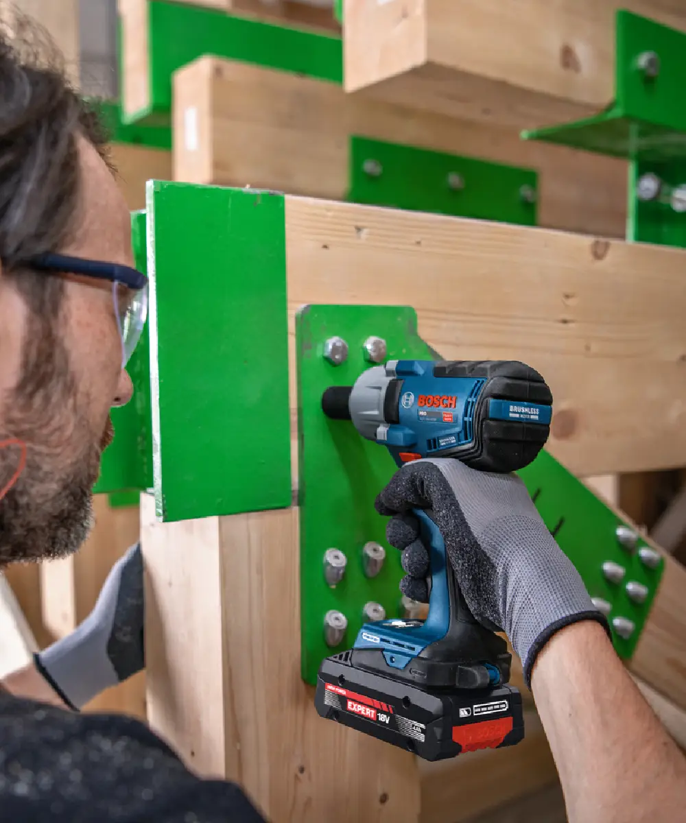 BOSCH PRO GDS18V-450P aku udarni odvijač u ruci osobe koja radi na drvenoj konstrukciji.