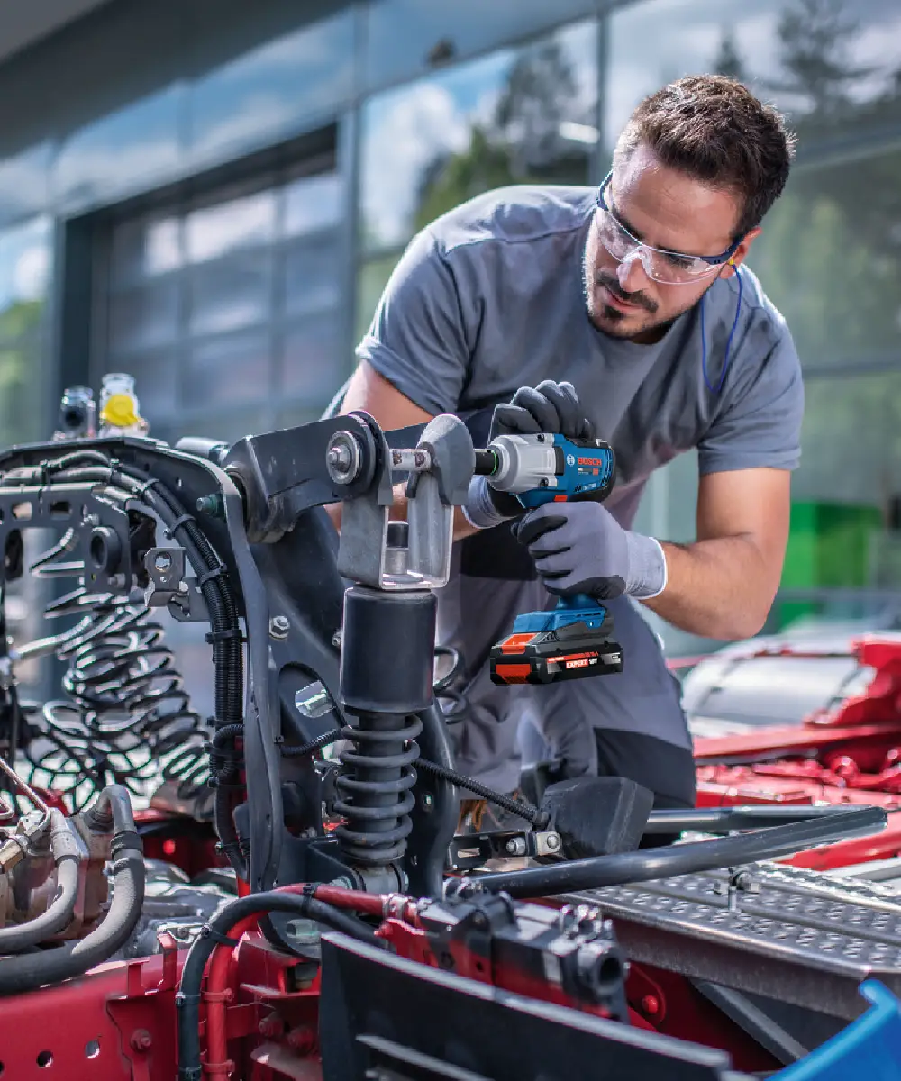 Čovjek koristi BOSCH aku udarni odvijač PRO GDS18V-450P na automobilu u radionici.