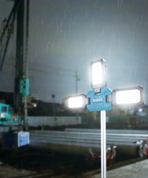 Makita ML014G aku svjetiljka na stativu s tri LED svjetla u kišnom okruženju.