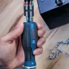 BOSCH PRO račni odvijač sa spremnikom i 12 bitova Bosch PRO električni odvijač s plavom ručkom i 12 raznih bitova u pozadini.