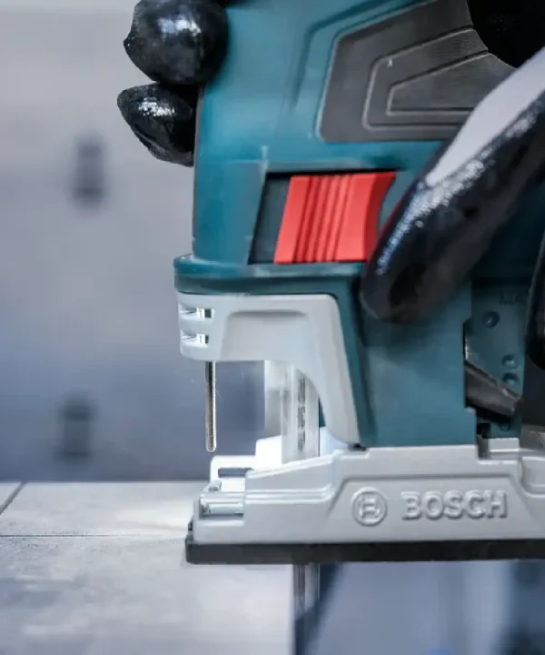Bosch ubodna pila s crvenim gumbom i dijelovima na metalnoj površini.