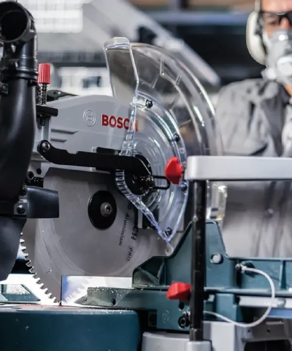 Bosch aku potezna pila za aluminij s zaštitnim poklopcem i radnikom u pozadini.