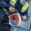 Radnik s zaštitnom opremom koristi električnu kružnu pilu za rezanje metala ili drva.