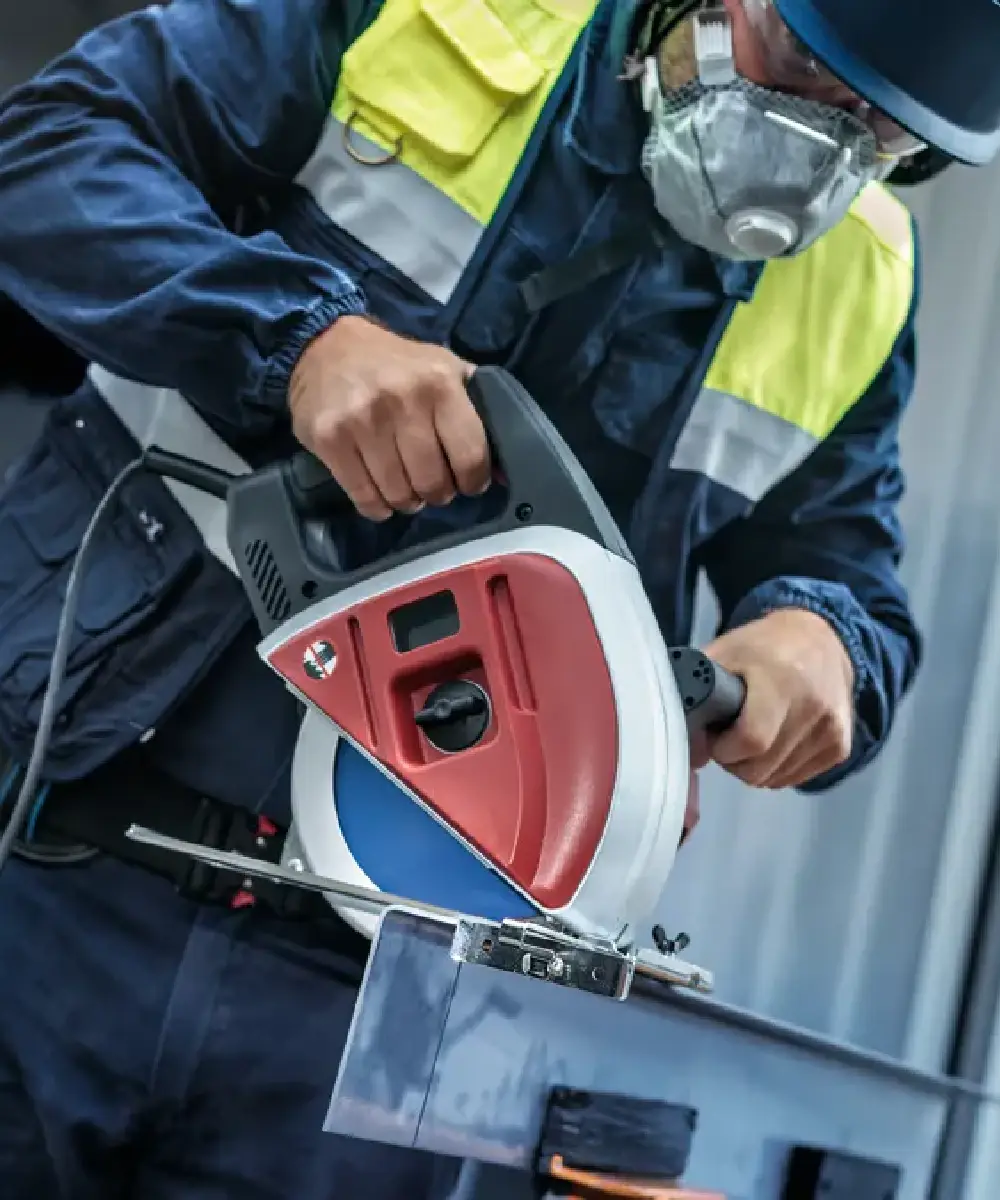 Radnik s zaštitnom opremom koristi električnu kružnu pilu za rezanje metala ili drva.
