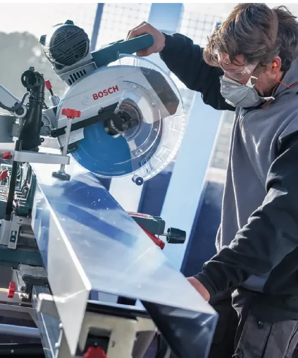 Radnik koristi Bosch kružnu pilu za rezanje aluminija u radionici.
