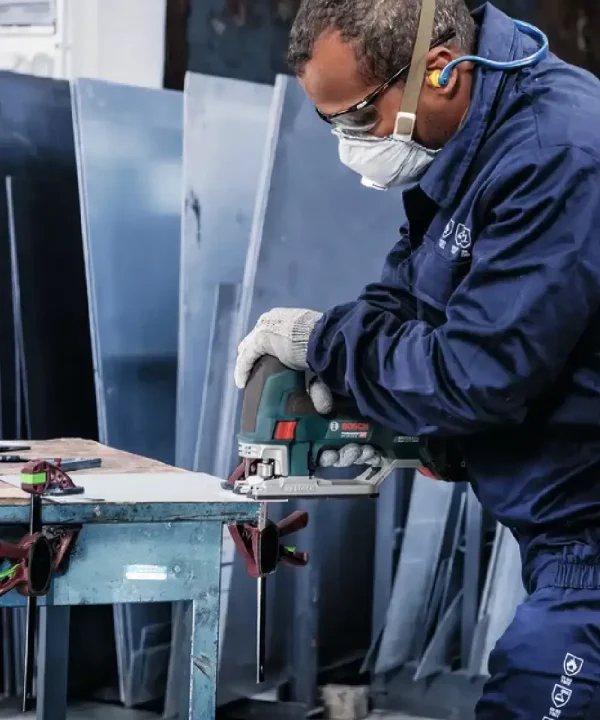 Radnik u zaštitnoj opremi koristi Bosch ubodnu pilu na metalnim profilmima.